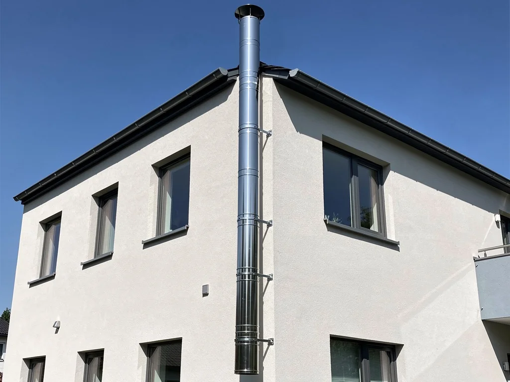 Conduit de fumée inox isolé installé le long d'une façade jusqu'à la toiture